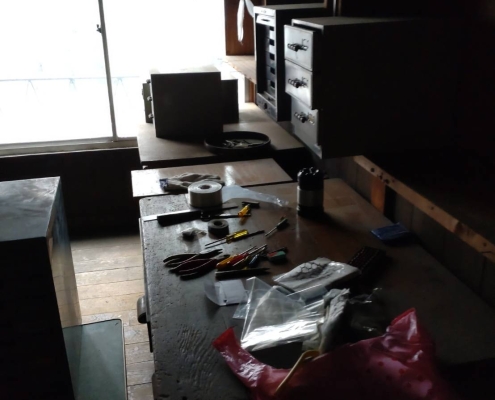 片付け前の作業台に残されたドライバーやペンチなどの工具類と電子部品の仕分け前の様子|東京都の工場片付け作業現場