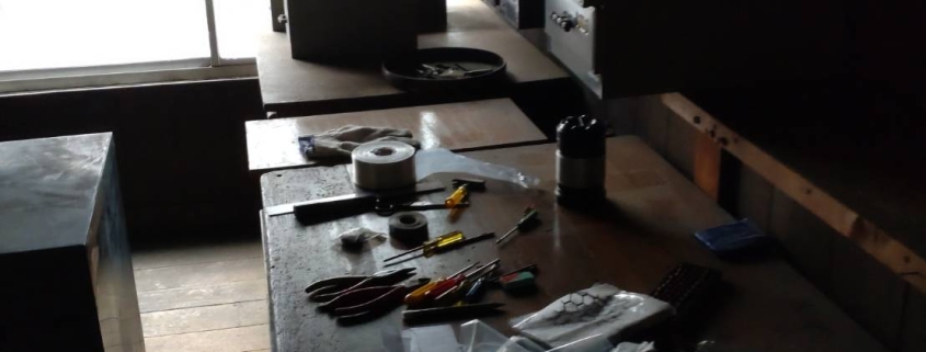 片付け前の作業台に残されたドライバーやペンチなどの工具類と電子部品の仕分け前の様子｜東京都の工場片付け作業現場