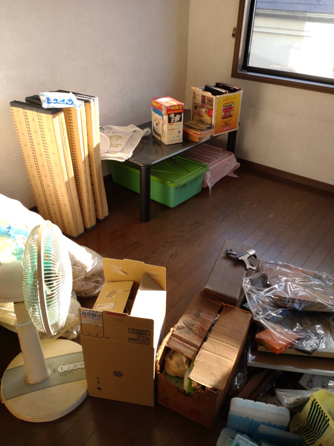 埼玉県久喜市の競売物件で生活雑貨や収納ケースが集まる居室の施工前状況